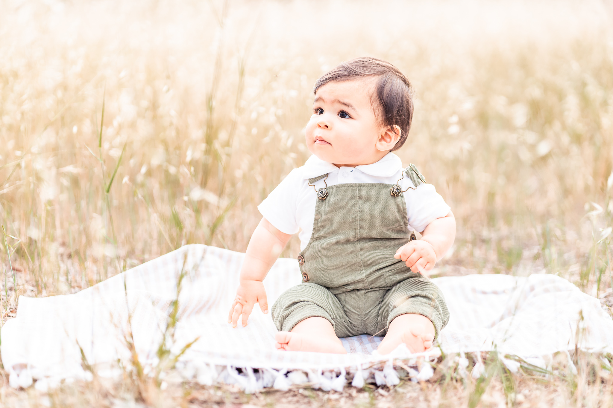 baby boy in sage green romper sitting in a grassy field