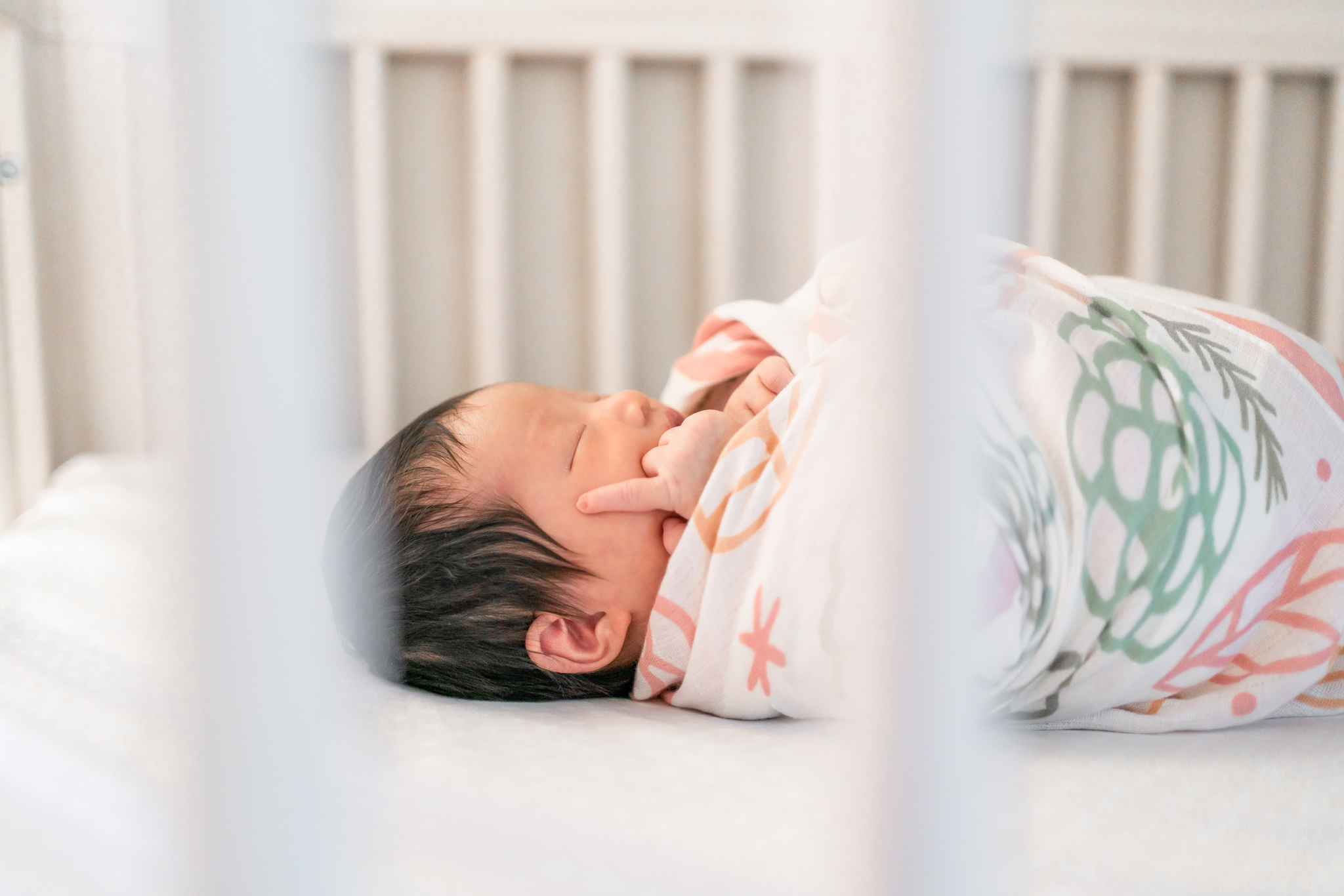 newborn baby swaddled in crib