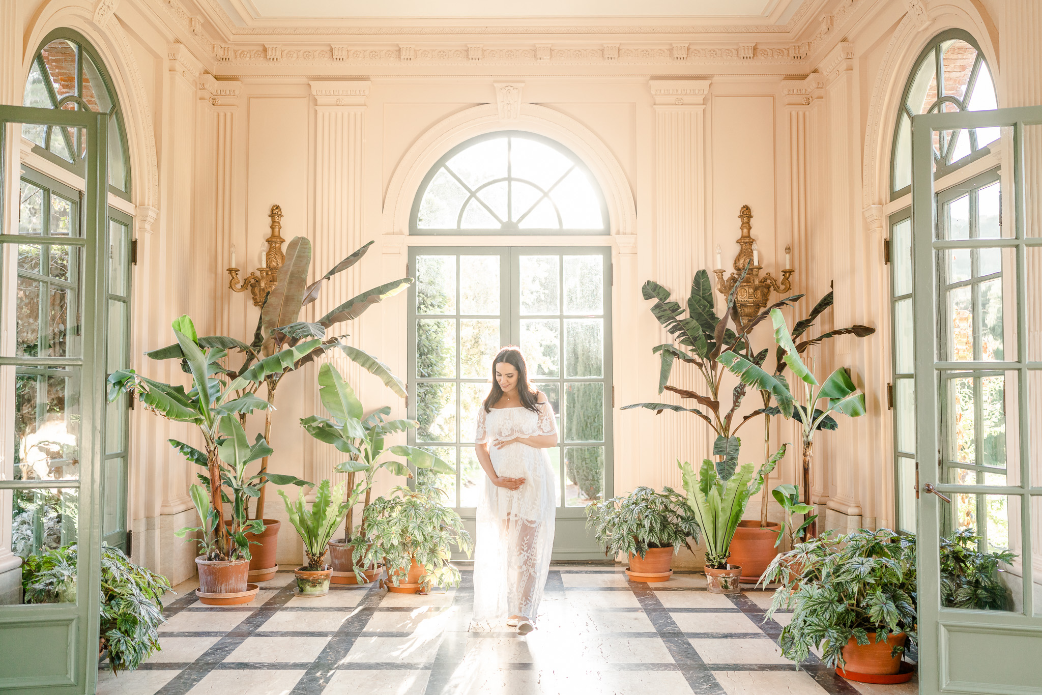 pregnant san francisco woman in a white gown in a beautiful white room surrounded by plants