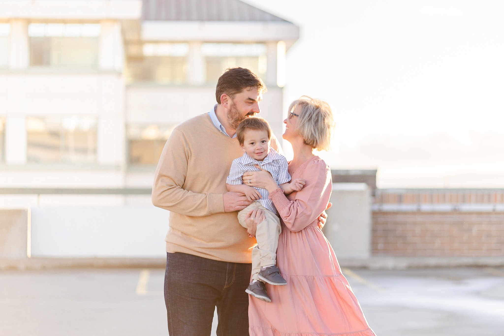 Bay area family of three on a rooftop in Oakland smiling at each other