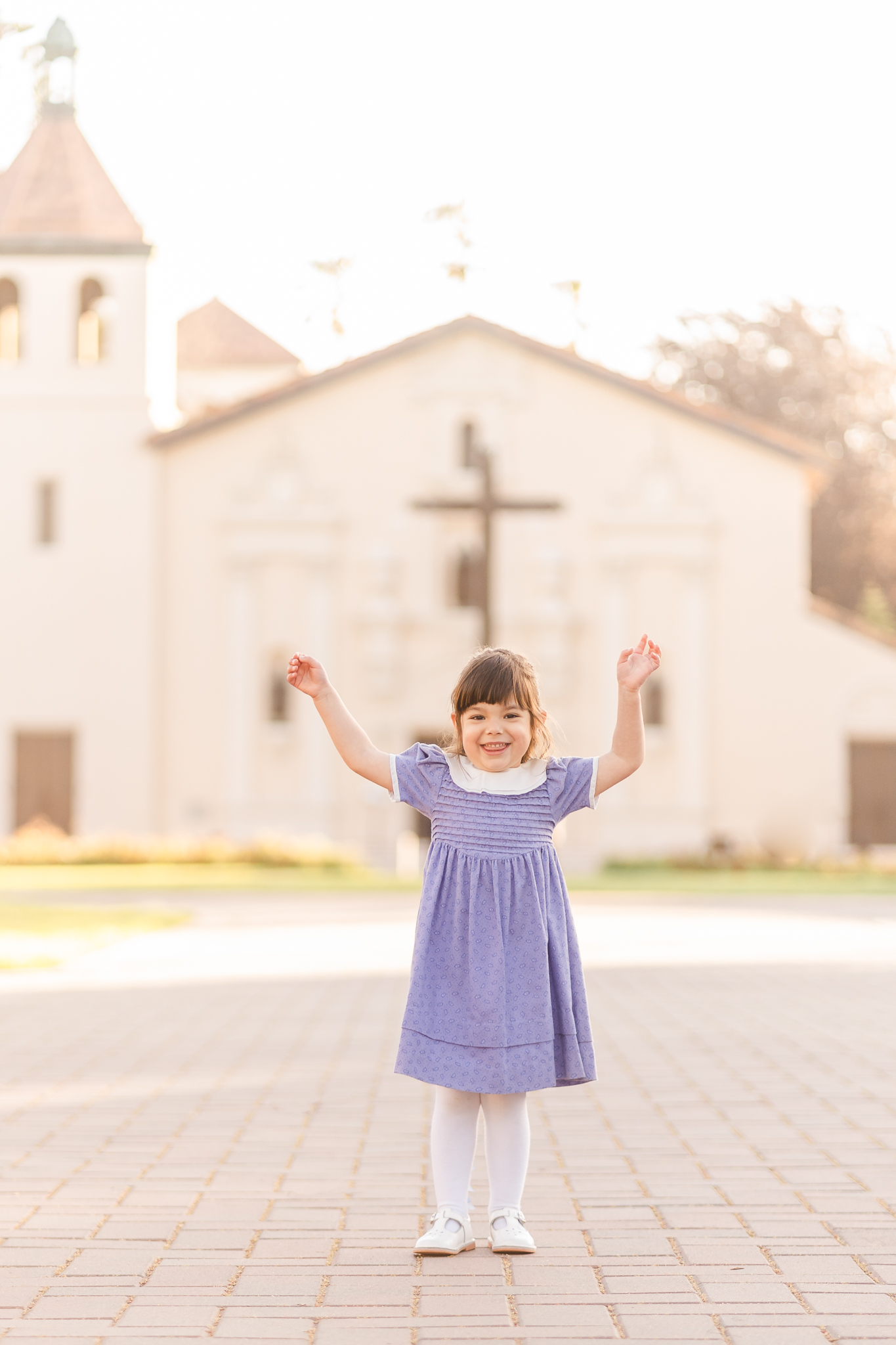 Little girl in a purple dress standing in front of the Santa Clara University mission church
