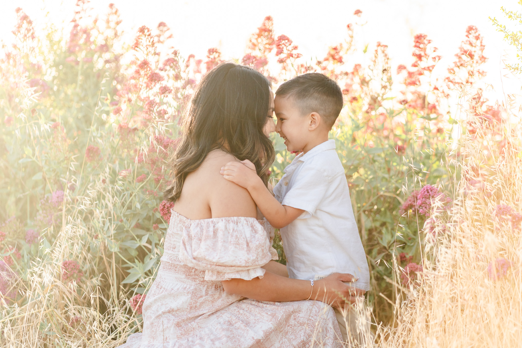 mom and young son touching noses in a field of flowers in the bay area