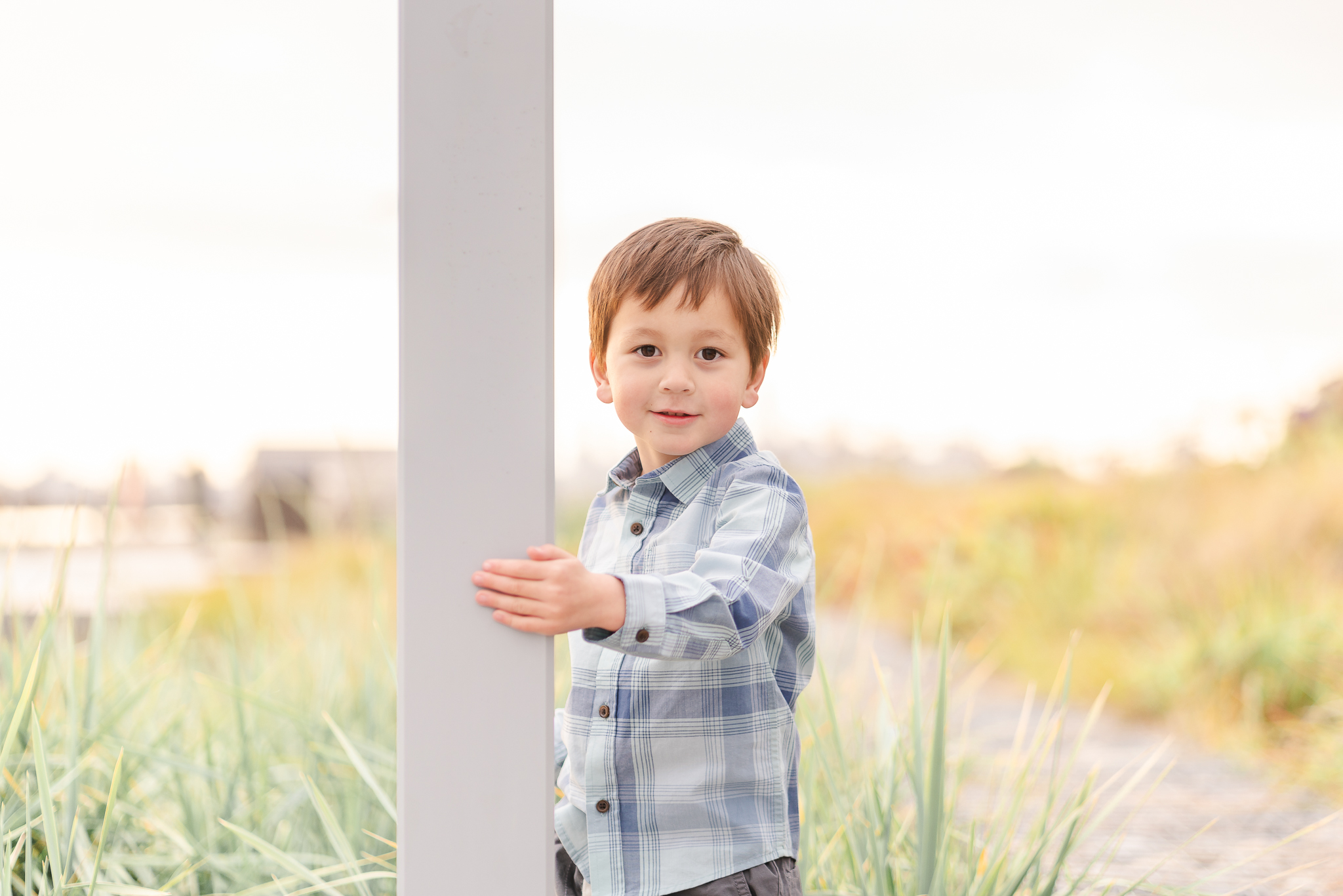 Preschool age boy holding onto a lamppost and smiling at the camera