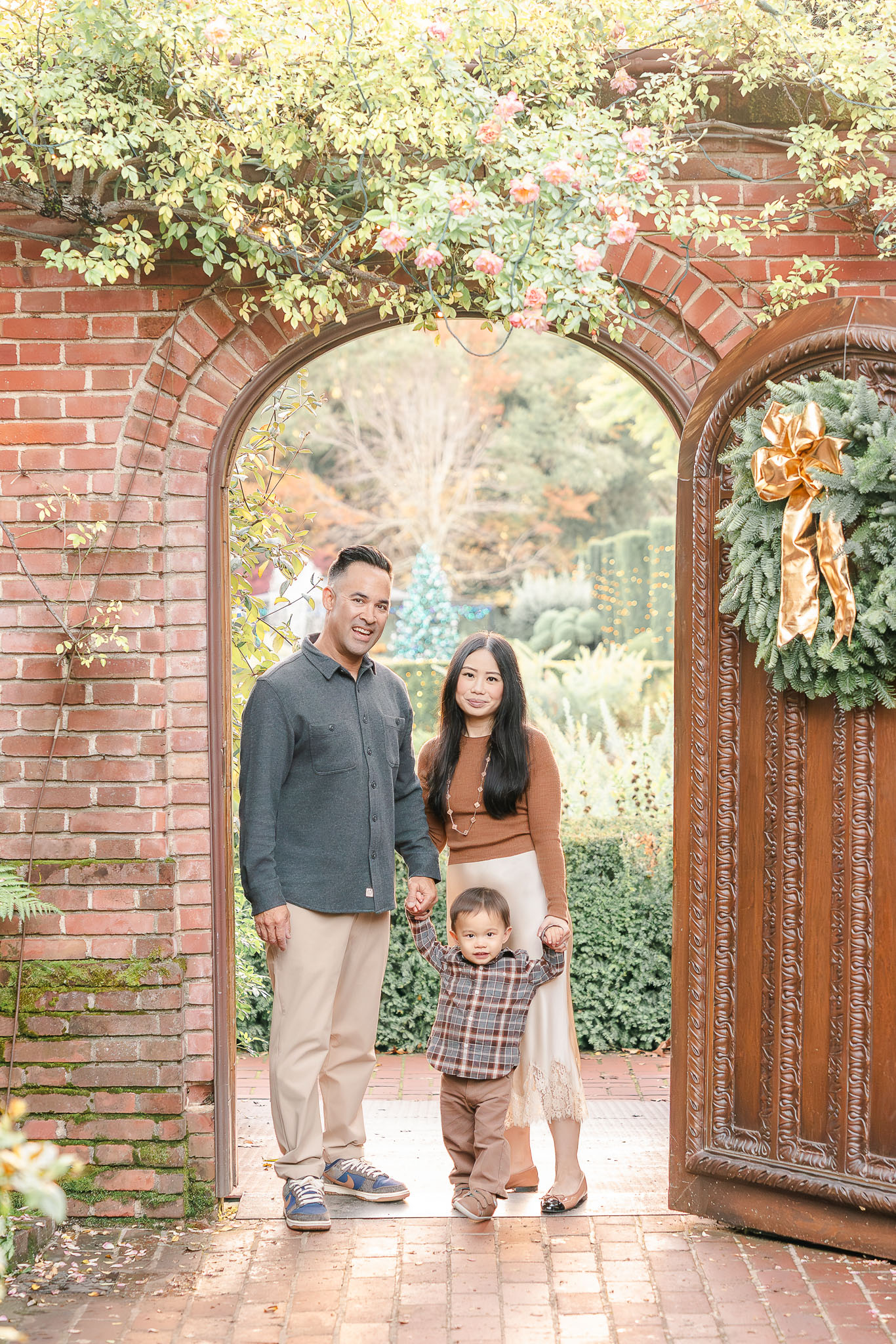mom dad and young son standing in an arched doorway during a holiday family photo session at filoli